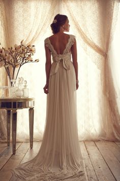 the back of a woman's dress in front of a window with sheer curtains