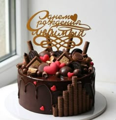 a cake with chocolate frosting and hearts on top sitting in front of a window