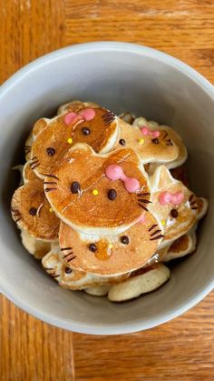 a bowl filled with hello kitty pancakes on top of a wooden table