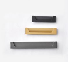 three black and gold paper holders on a white wall, one with a yellow handle