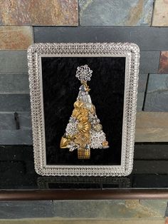 a christmas tree made out of gold and silver beads on a black background with an ornate frame