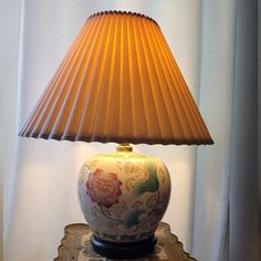 a lamp that is sitting on top of a table next to a curtained window