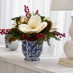 a blue and white vase filled with flowers on top of a table next to a lamp