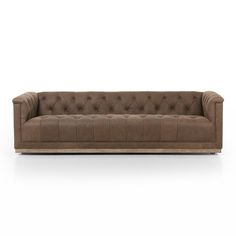 a brown leather couch with buttons on the back and arms, in front of a white background