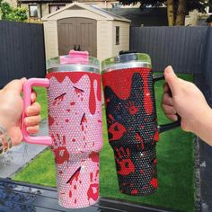 two people holding up their mugs in front of a house