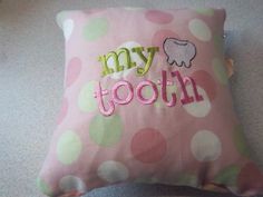 a pink and green polka dot pillow with the words my tooth embroidered on it's side