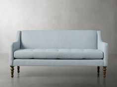 a blue couch sitting on top of a hard wood floor next to a gray wall