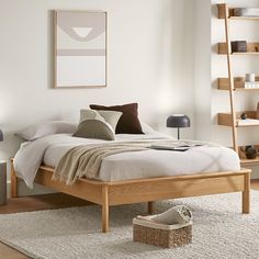 a bed sitting in a bedroom on top of a wooden floor next to a book shelf