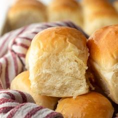 several rolls are piled on top of each other in a basket with red and white striped towels