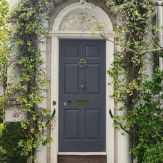 a black door surrounded by white flowers and greenery