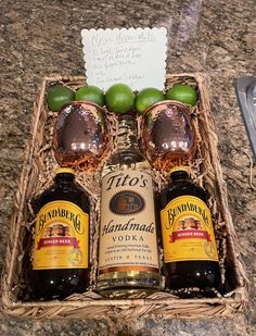 two bottles of liquor in a wicker basket with limes and an empty note