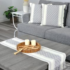 a living room with grey couches, white pillows and candles on the coffee table