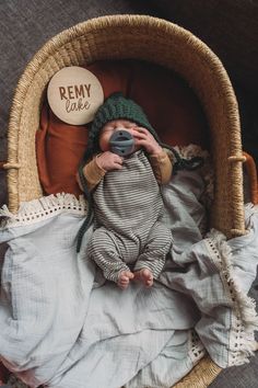 a baby laying in a basket with a camera