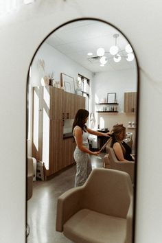 a woman is getting her hair done in a salon with another woman sitting at the counter