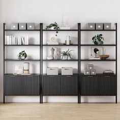 a black bookcase with plants and books on it against a white wall in an empty room