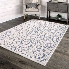 a living room area with a chair, table and rug on the hardwood flooring