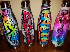 three different colored bottles with graffiti written on them