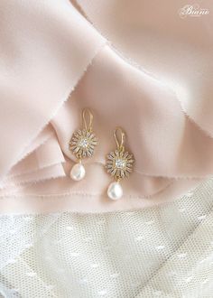 two pairs of earrings on top of a pink cloth