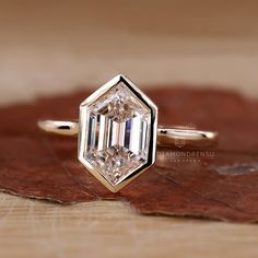 a diamond ring sitting on top of a wooden table next to a brown maple leaf