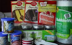 some food items are sitting on the counter top next to cans and spoons, including cake mix