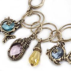 a close up of a keychain with charms on it's sides and an owl charm hanging from the front