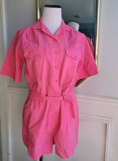 "This amazing vintage outfit by Ivory of Miami, Florida is ready to be worn again! This one-piece outfit is a vibrant pink all over. It has short sleeves and shorts on bottom with a slight split on sides of leg. There is elastic in the waist and a belt that buckles in front. The romper buttons down the front with a slightly pointed collar atop. There is a buttoning pocket on each side of chest.  Sized: Medium ( approx 6/8) waist: 16\" unstretched across front Chest: 19 across front length: 31\" Retro Cotton Short Sleeve Jumpsuit, Pink Retro Jumpsuits And Rompers For Spring, Retro Summer Jumpsuits And Rompers With Pockets, Vintage Cotton Jumpsuits With Short Sleeves, Retro Short Sleeve Jumpsuits And Rompers With Pockets, Vintage Cotton Jumpsuits And Rompers With Short Sleeves, Retro Pink Jumpsuits And Rompers For Summer, Vintage Cotton Short Sleeve Jumpsuits And Rompers, Retro Jumpsuits And Rompers With Pockets