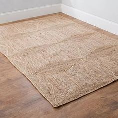 a rug on the floor in a room with hardwood floors and white walls, along with a wooden floor