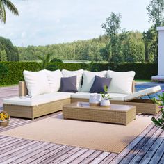 a couch and coffee table on a wooden deck next to a swimming pool with palm trees in the background