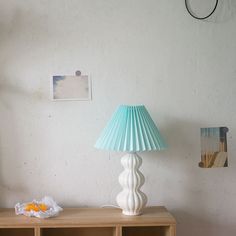 a white lamp sitting on top of a wooden table next to a book case and pictures