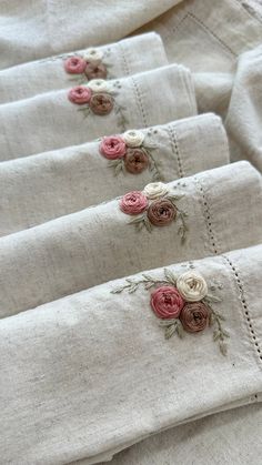 four linen napkins with embroidered flowers on them are lined up next to each other