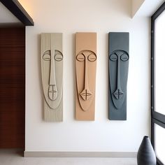 three abstract sculptures are hanging on the wall