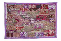 a purple and pink patchwork wall hanging with various designs on the front, along with an intricately designed border