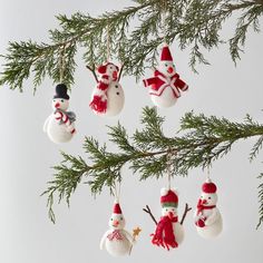 christmas ornaments hanging from a tree branch with snowmen and santa hats on it's ornament