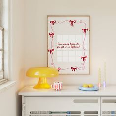 a yellow table lamp sitting on top of a white dresser next to a framed picture