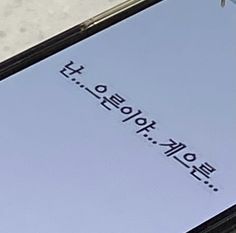 an open cell phone sitting on top of a white counter next to a sign that says,