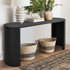 a black console table with two baskets on top and a lamp next to it in the corner