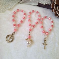 three rosarys with pink pearls and a cross on one beaded necklace, the other pearled