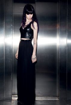 a woman standing in front of an elevator wearing a black skirt and cropped top