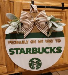 a starbucks sign hanging from the side of a wooden door with a bow on it