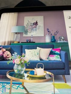 a living room with a blue couch and coffee table in front of a purple wall