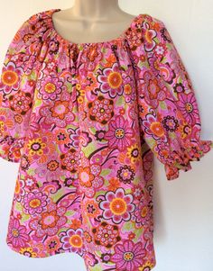 This handmade blouse is made in a 1960's style with puffy sleeves and elastic neckline. The fabric is a polyester/cotton seersucker with the wrinkling or puckering in it. It is sized 12-14 misses. The neckline and short sleeves are gathered with elastic. The print is bright floral great for spring and summer. This blouse can easily be worn by teen to adult. Multicolor Fitted Blouse With Balloon Sleeves, Fitted Multicolor Blouse With Balloon Sleeves, Fitted Multicolor Balloon Sleeve Blouse, Spring Retro Blouse With Ruffles, Retro Ruffled Blouse For Spring, Pink Floral Print Blouse With Balloon Sleeves, Pink Blouse With Balloon Sleeves And Floral Print, Pink Balloon Sleeve Blouse With Floral Print, Cotton Peasant Top With Puff Sleeves And Floral Print