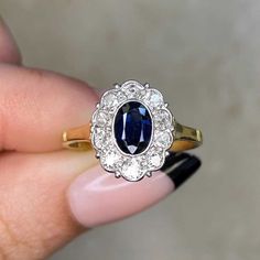 This item has just been reserved by another customer. Please contact us to be notified if it becomes available.  This beautiful vintage cluster ring showcases a genuine bezel-set central sapphire weighing around approx 0.50 carats. Surrounding the gemstone are several old Europan-cut diamonds, collectively weighing approx 0.60 carats. Crafted during the Edwardian era around 1900, this ring is fashioned from 18k yellow gold.  ✦ GEMSTONE SPECIFICATIONS: Center Gemstone: Sapphire  Sapphire Weight: Timeless Oval Sapphire Ring Vvs Clarity, Timeless Oval Sapphire Ring With Vvs Clarity, Oval Brilliant Cut Sapphire Ring, Timeless Oval Sapphire Ring With Prong Setting, Timeless Oval Sapphire Diamond Ring, Oval Sapphire Ring With Vvs Clarity, Oval Sapphire Ring With Rose Cut Diamonds, Oval Platinum Sapphire Ring, Vintage Sapphire Oval Cluster Ring