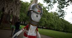 a statue of a knight is standing in front of a building with people walking by