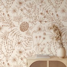 a vase with flowers on top of a wooden cabinet in front of a wallpaper