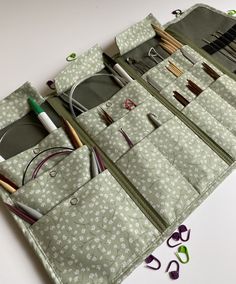 an assortment of sewing tools and accessories in a green case on a white table top