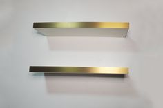 two gold and silver shelf brackets on a white wall