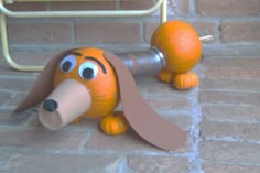 a toy dog made to look like it is laying on the ground next to a brick wall