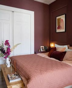 a bed with pink comforter and pillows in a bedroom