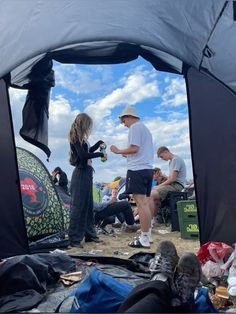 a group of people standing in front of a tent on top of a dirt field