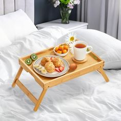 a tray with food on it sitting on top of a bed next to a cup of coffee